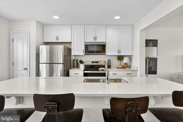 a kitchen with stainless steel appliances a refrigerator a stove a sink a dining table and chairs