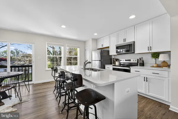 a kitchen with stainless steel appliances granite countertop a table chairs refrigerator and sink