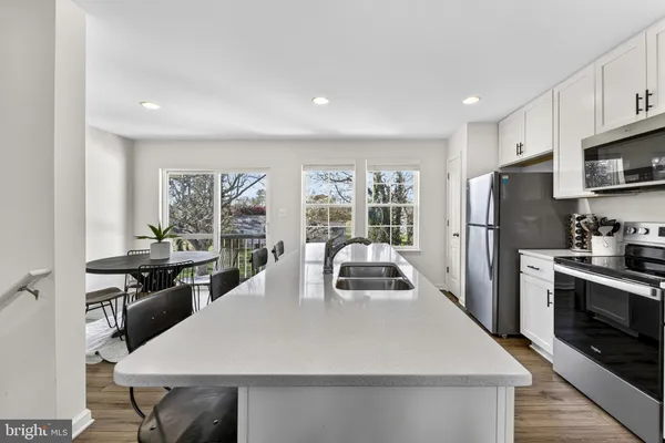 a kitchen with stainless steel appliances a stove a refrigerator a sink and a stove with white cabinets
