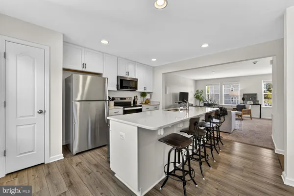 a kitchen with stainless steel appliances a refrigerator a stove a sink a dining table and chairs