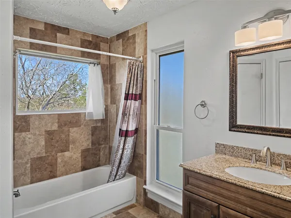 a en suite bathroom with a granite countertop sink and a mirror