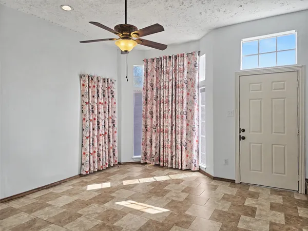 an empty room with windows and fan