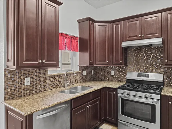 a kitchen with granite countertop a sink stove and cabinets