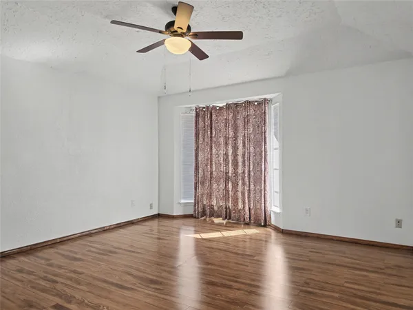 a view of empty room with wooden floor and fan