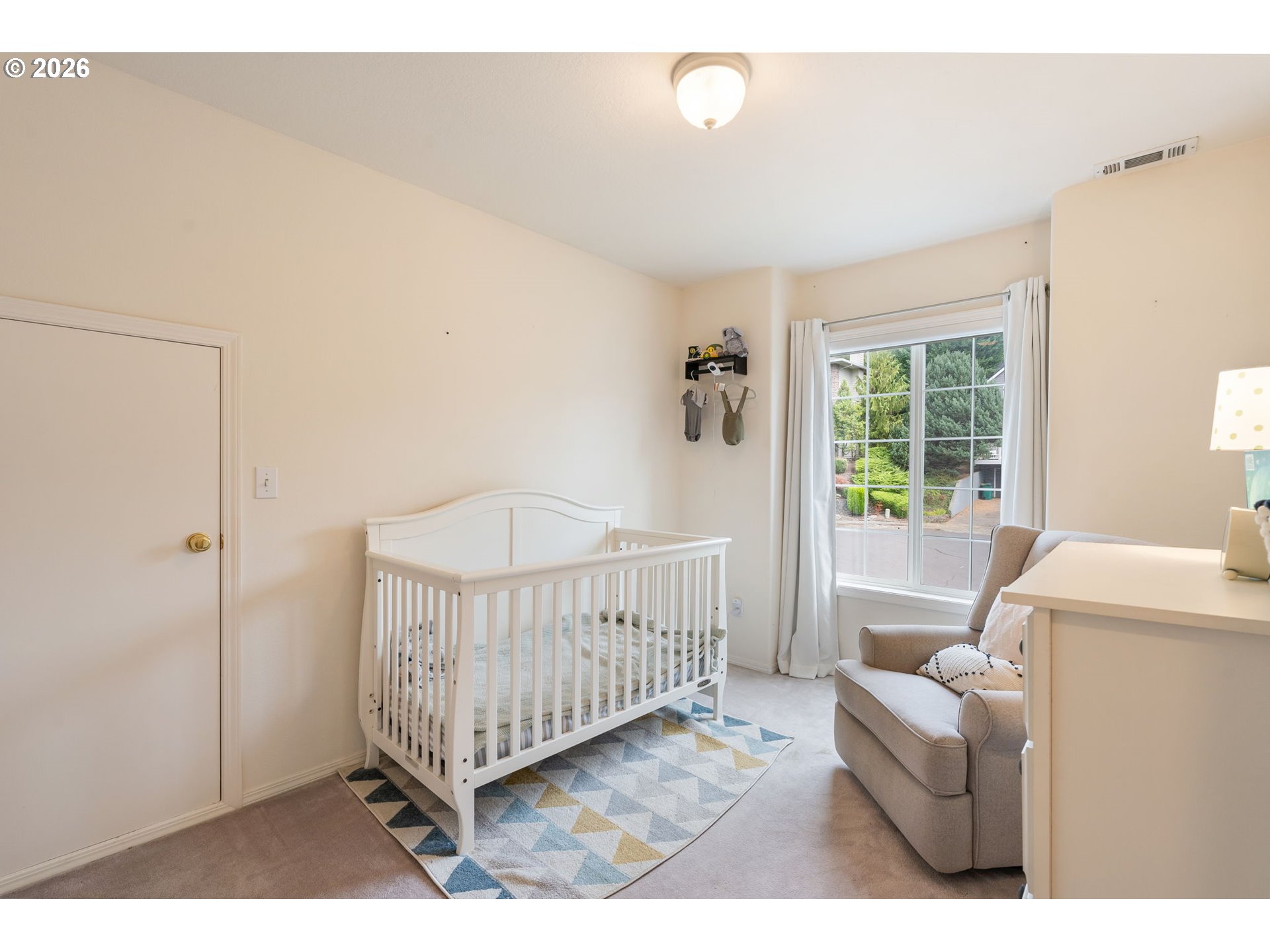 8943 Southwest 149th Place Beaverton, OR 97007 - Photo 29 of 41 a living room with a baby crib furniture a chandelier and a window