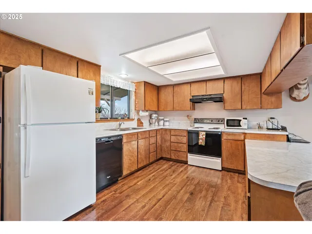 a kitchen with stainless steel appliances granite countertop a refrigerator a sink dishwasher a stove and a microwave oven with cabinets