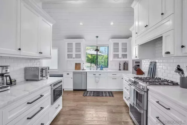 a kitchen with stainless steel appliances white cabinets a stove top oven a sink and dishwasher
