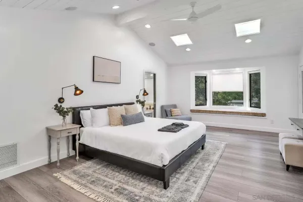a large bedroom with a bed and wooden floor