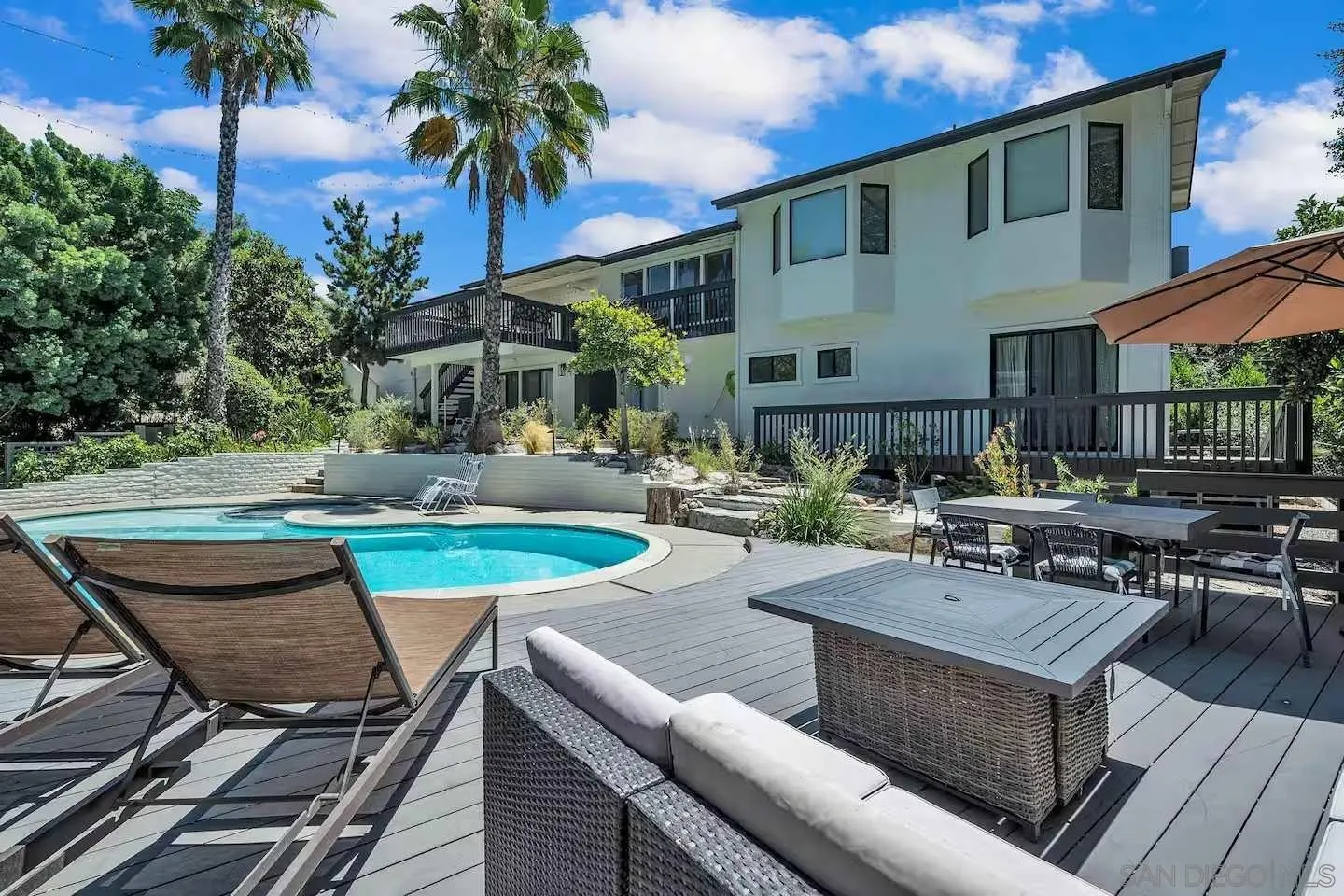 3550 Laketree Drive Fallbrook, CA 92028 - Photo 32 of 56 a view of a patio with couches table and chairs under an umbrella with palm trees