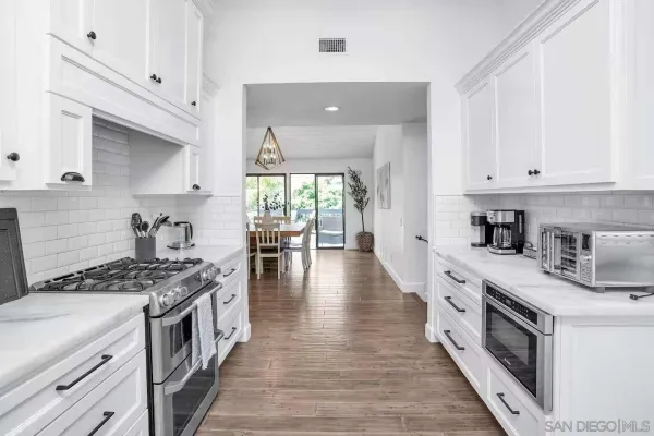 a kitchen with stainless steel appliances granite countertop a stove a sink dishwasher and a refrigerator with wooden floor