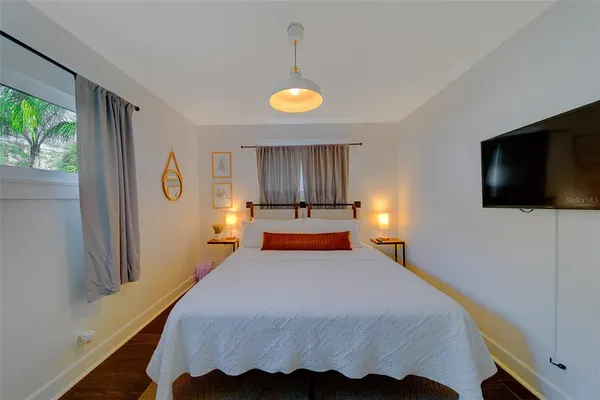 a bedroom with a bed a couch and a flat tv screen on a dresser