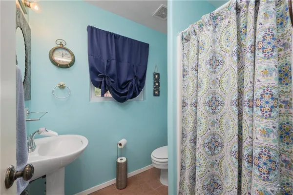 a bathroom with a toilet sink and shower curtain