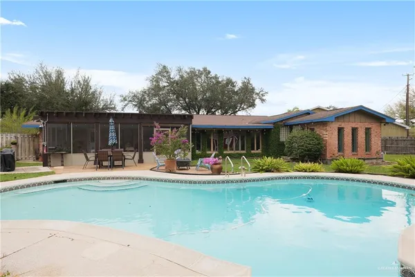a view of swimming pool with lawn chairs and large trees