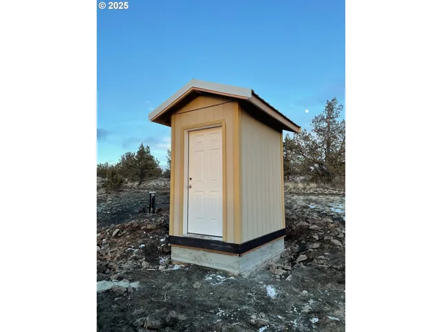 a view of a house with a small yard and large tree