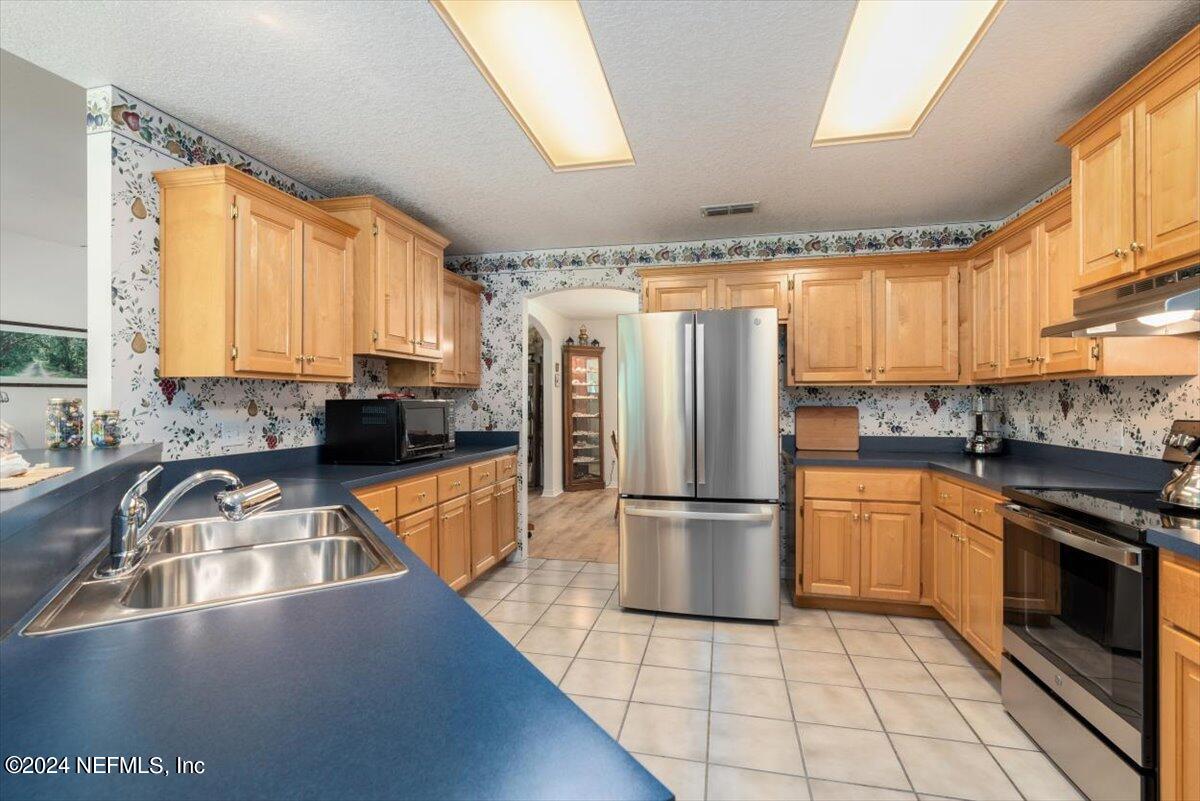 6481 Brooklyn Bay Road Keystone Heights, FL 32656 - Photo 16 of 45 a kitchen with a refrigerator a sink and white cabinets