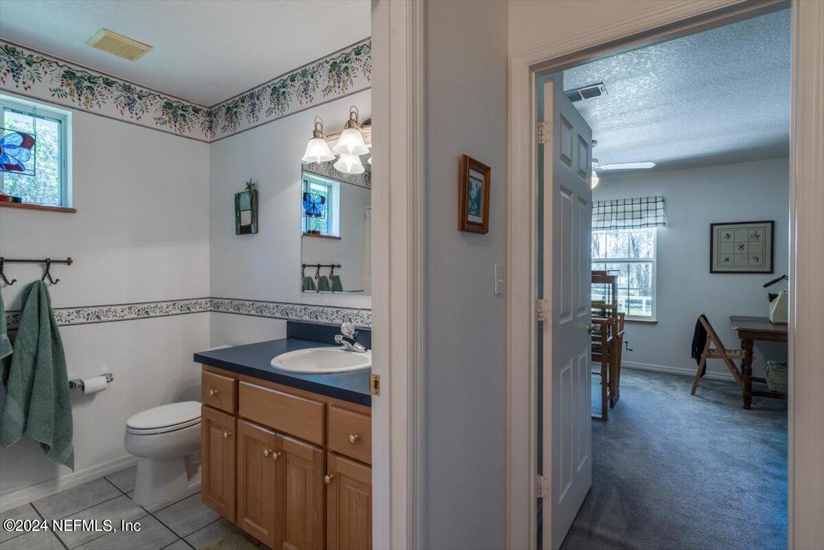 6481 Brooklyn Bay Road Keystone Heights, FL 32656 - Photo 26 of 45 a bathroom with a granite countertop sink mirror vanity and toilet