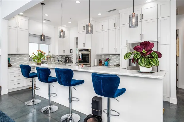 a kitchen with stainless steel appliances granite countertop a sink a refrigerator and a white cabinets