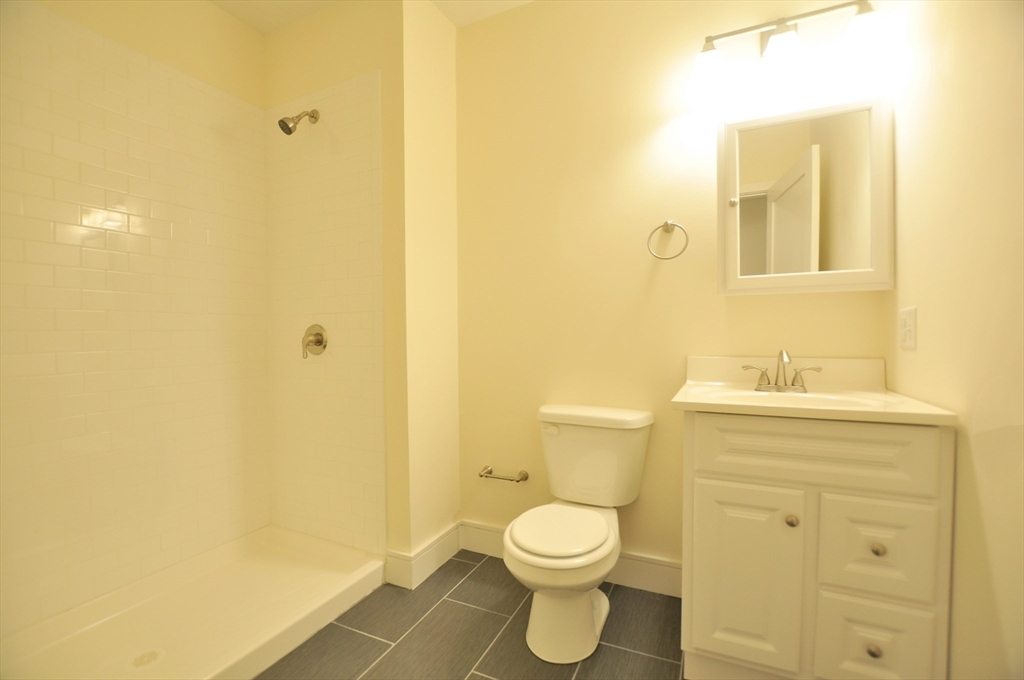 877 Beacon Street, Unit 1 Boston, MA 02215 - Photo 3 of 12 a bathroom with a toilet a sink a vanity and mirror