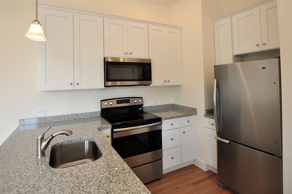 877 Beacon Street, Unit 1 Boston, MA 02215 - Photo 9 of 12 a kitchen with white cabinets and stainless steel appliances