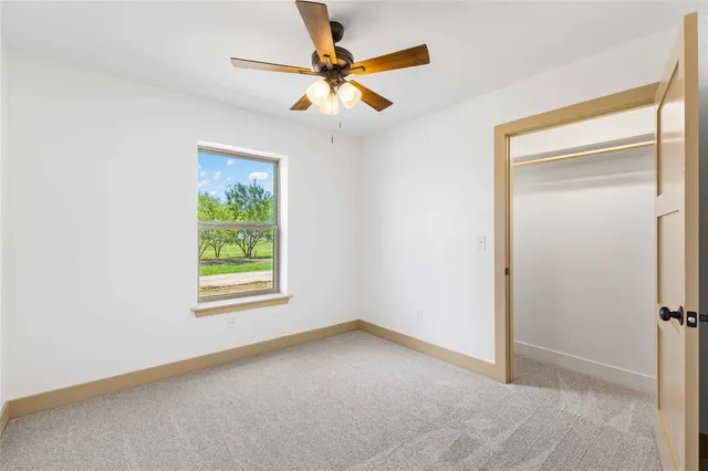 an empty room with wooden floor cabinet and windows