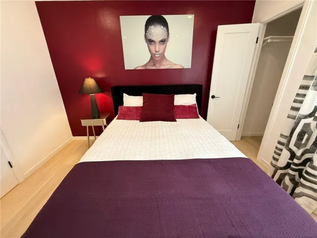 a bed sitting in a bedroom next to a window with wooden floor