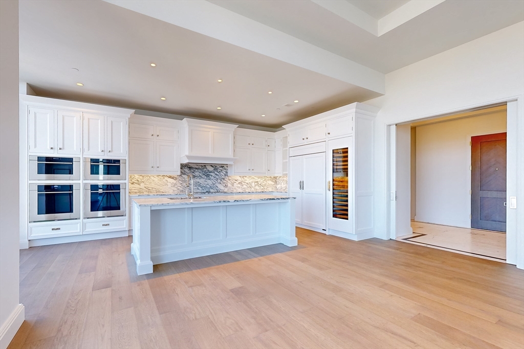 240 Devonshire Street, Unit PH1A Boston, MA 02110 - Photo 7 of 40 a large kitchen with kitchen island a sink stainless steel appliances and cabinets