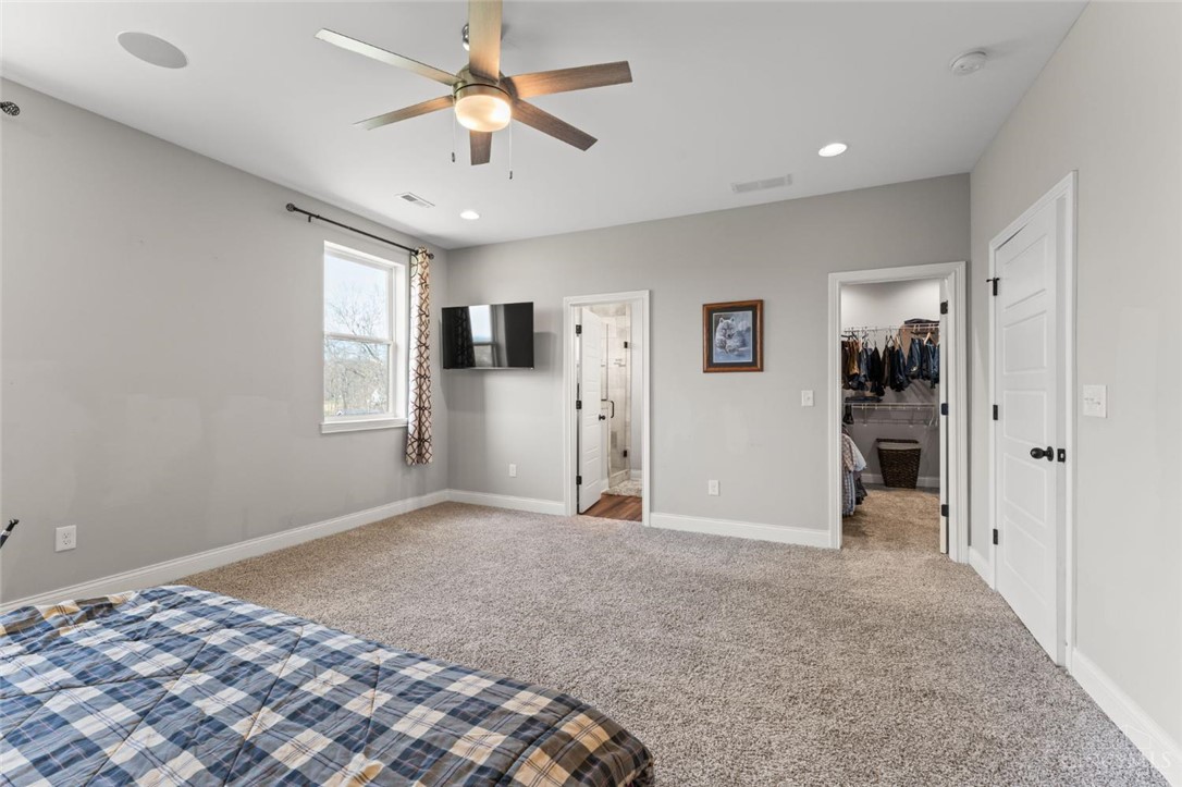 2425 Middleboro Road Clarksville, OH 45113 - Photo 64 of 91 This spacious primary bedroom features soft carpeting, a ceiling fan, and access to a large walk-in closet.