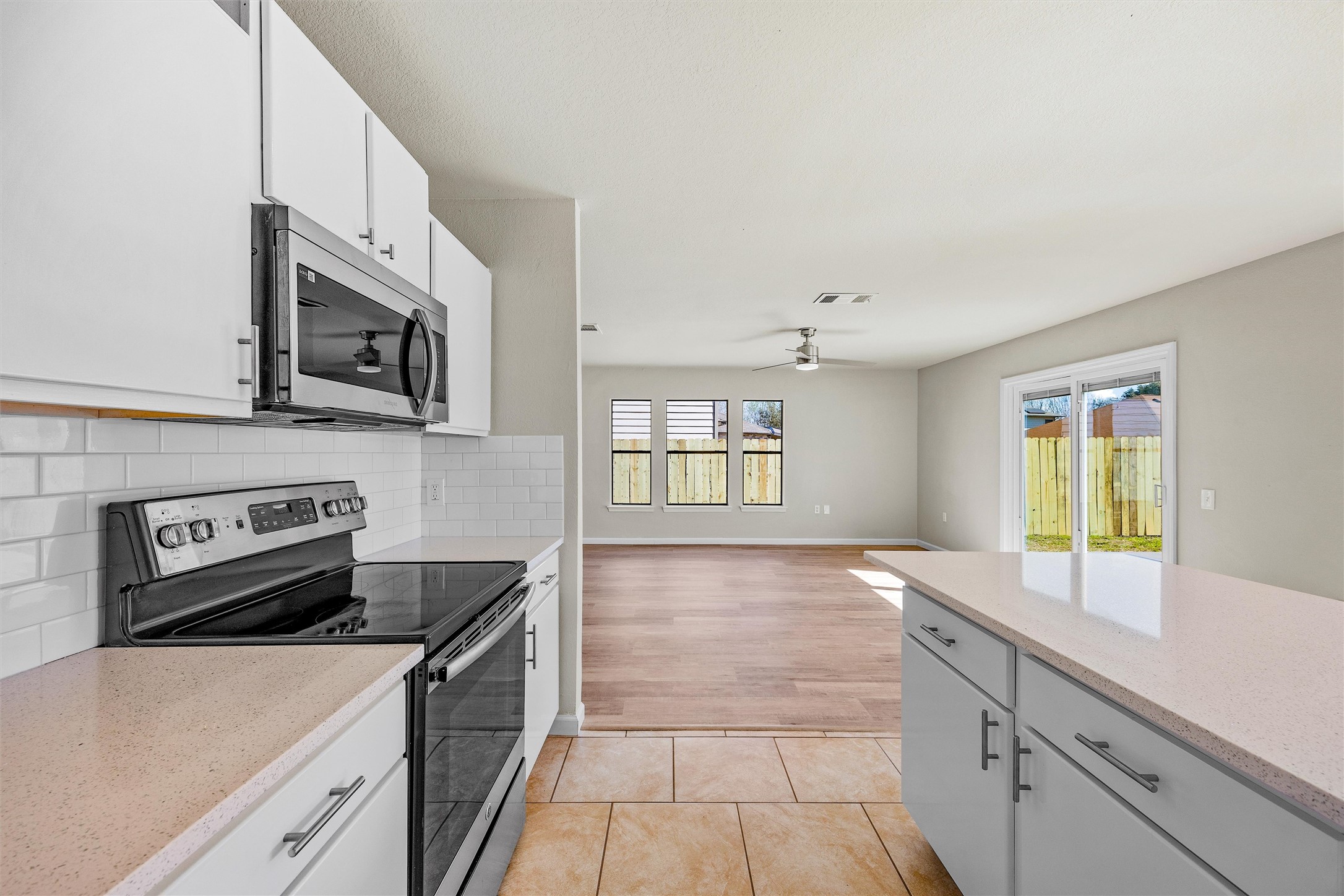7541 Redrick Drive Austin, TX 78747 - Photo 19 of 40 Kitchen with light tile patterned floors, a healthy amount of sunlight, visible vents, decorative backsplash, and appliances with stainless steel finishes
