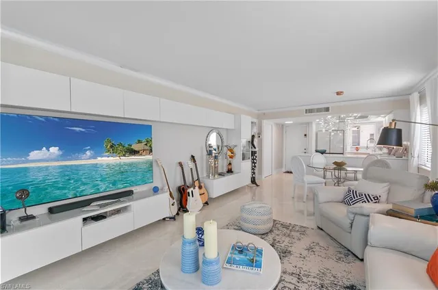 a living room with furniture floor to ceiling window and a kitchen view