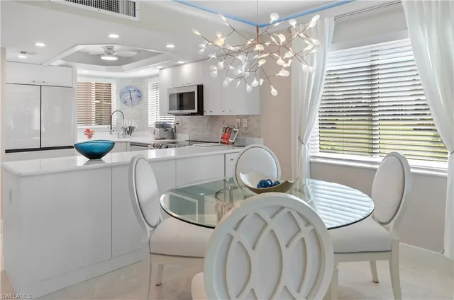 a kitchen with stainless steel appliances kitchen island granite countertop a dining table chairs and a sink