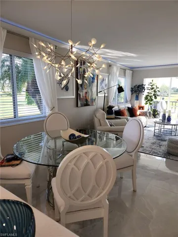 a living room with furniture a chandelier and a floor to ceiling window