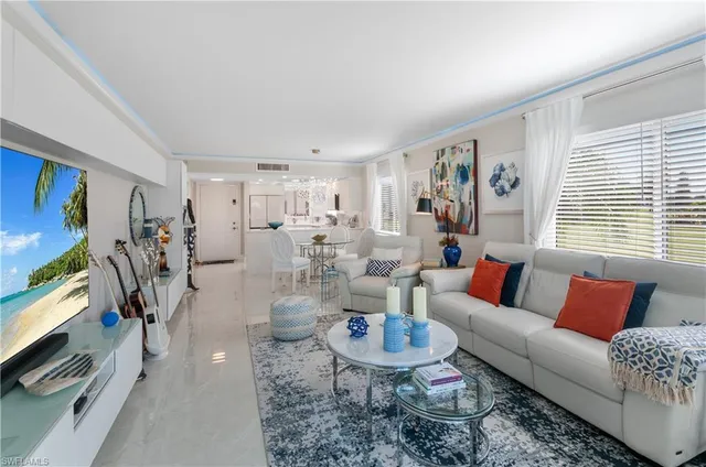 a living room with furniture kitchen view and a window