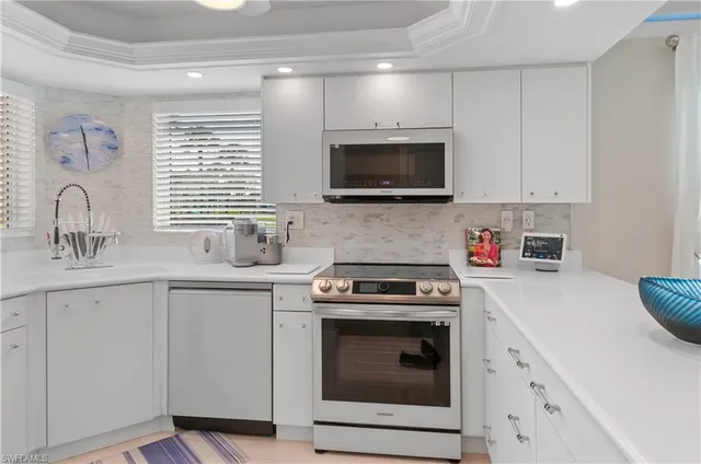 a kitchen with cabinets stainless steel appliances a sink and a window