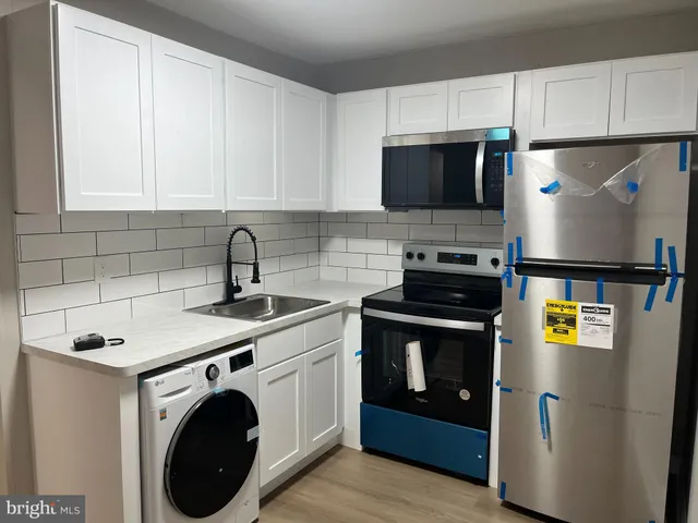 a kitchen with stainless steel appliances a stove a sink a refrigerator a microwave and cabinets