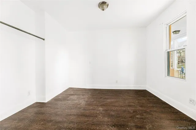 an empty room with wooden floor fireplace and windows