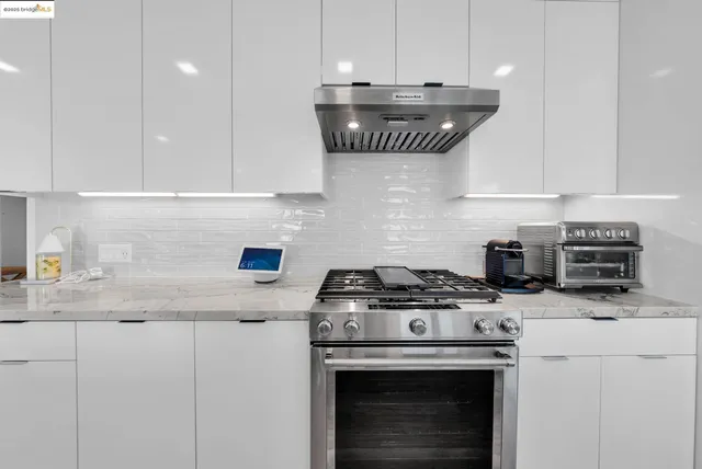 a kitchen with stainless steel appliances granite countertop a sink a stove and a white cabinets