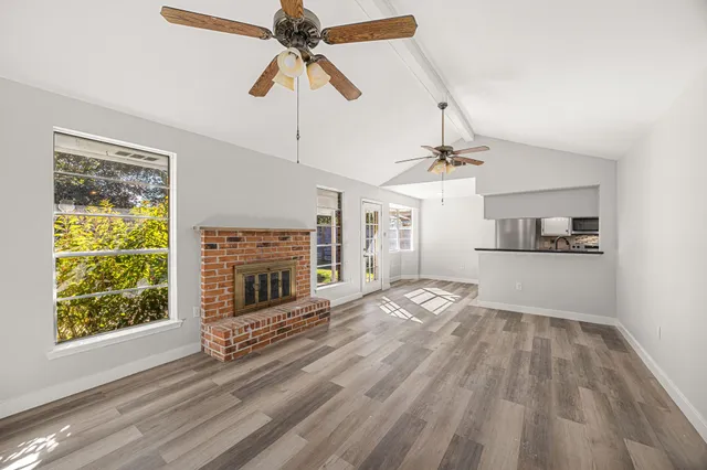 a view of empty room with wooden floor fireplace and a window