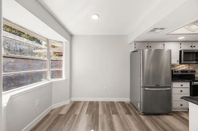 a view of a kitchen with wooden floor and electronic appliances