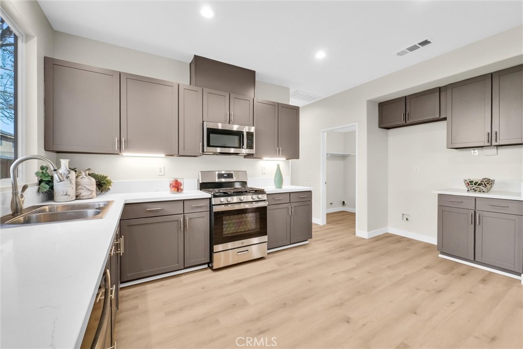 6732 Rico Court Eastvale, CA 92880 - Photo 12 of 30 a kitchen with stainless steel appliances granite countertop a sink stove and refrigerator