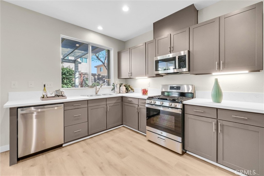 6732 Rico Court Eastvale, CA 92880 - Photo 13 of 30 a kitchen with stainless steel appliances granite countertop a stove a sink and a microwave