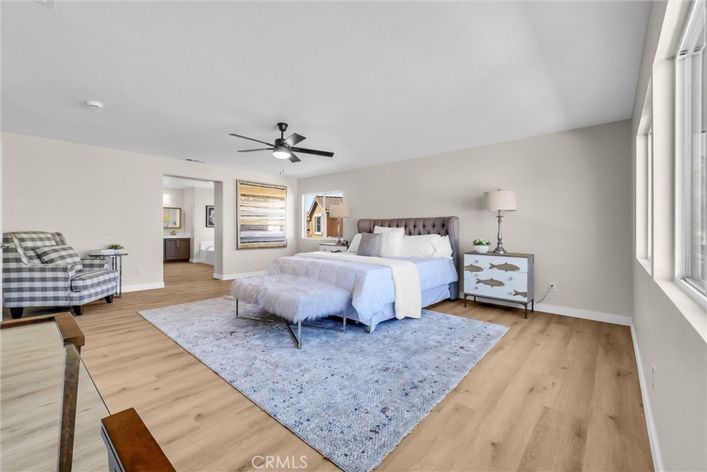 6732 Rico Court Eastvale, CA 92880 - Photo 15 of 30 a spacious bedroom with a bed a couch and a window