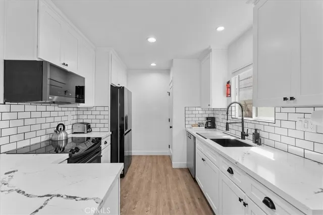 a kitchen with granite countertop a sink stainless steel appliances and cabinets