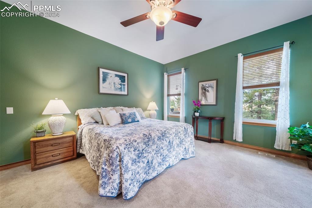 8174 Inca Road Larkspur, CO 80118 - Photo 26 of 50 a spacious bedroom with a bed and a chandelier