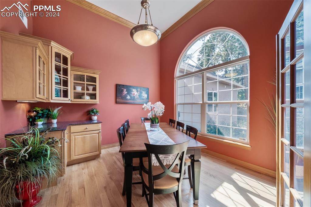 8174 Inca Road Larkspur, CO 80118 - Photo 8 of 50 a dining room with wooden floor a chandelier a wooden table and chairs