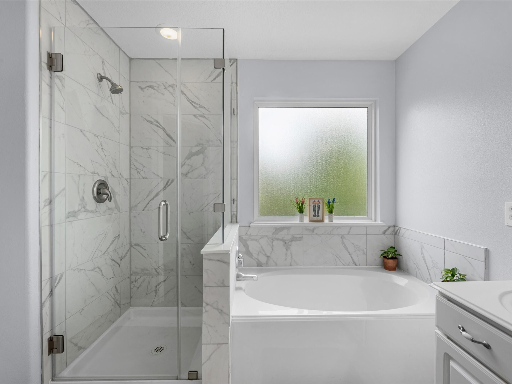 22422 Lamaster Lane Spring, TX 77373 - Photo 22 of 35 Sleek glass-enclosed shower with marble tile and a spacious soaking tub. The frosted window provides privacy while allowing natural light flow into the space.