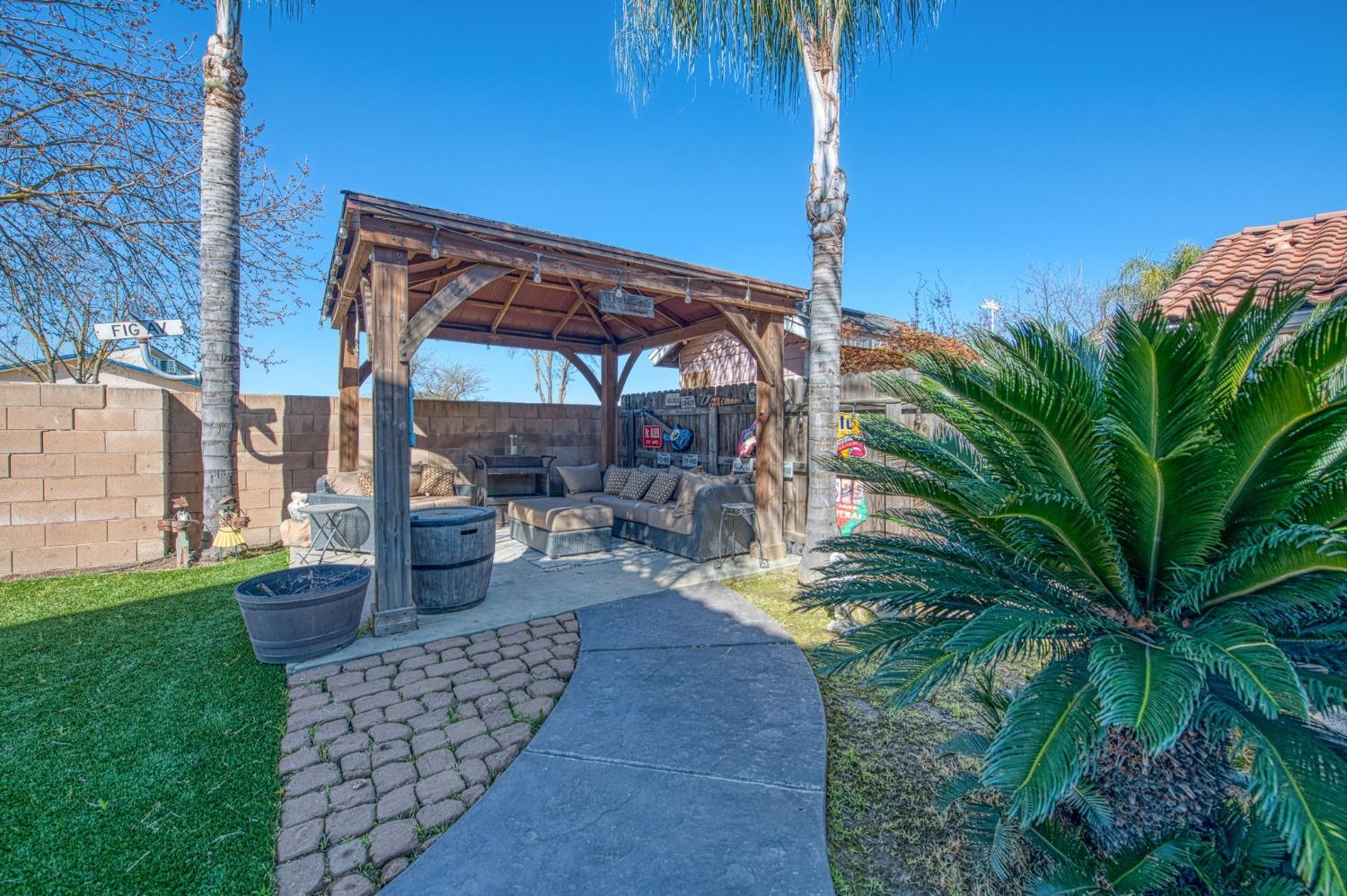 901 Maple Street Parlier, CA 93648 - Photo 50 of 67 a view of a patio with table and chairs potted plants and palm trees