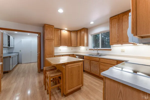 a kitchen with stainless steel appliances granite countertop wooden cabinets a sink and dishwasher a stove with wooden floor