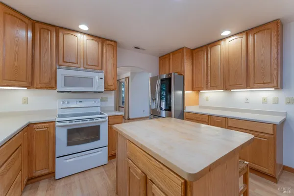 a kitchen with kitchen island a stove a sink and a refrigerator with wooden floor