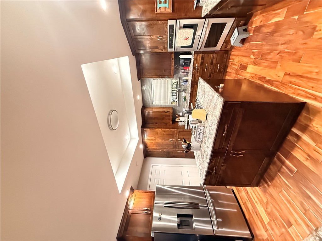 1224 River Road Pottsville, AR 72858 - Photo 28 of 37 Kitchen featuring wood-finish flooring, a central island with a light-toned countertop, dark wood cabinetry, and stainless steel appliances including a refrigerator and double wall oven