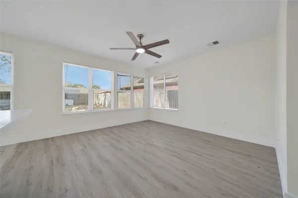 a view of an empty room with a window and wooden floor